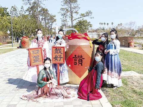 在「防疫優先」的大前提下，金門縣政府順勢將今年春節定位為「防疫平安年」，雖然大幅減少春節群聚活動，但也全力營造年節氛圍，圖為林務所與金酒公司及書法協會合作，邀請書法大師在報廢酒甕上書寫吉祥話與春聯，營造「酒香藝文大道」特色景點，希望與鄉親攜手共度「牛轉乾坤」的新年。（縣府提供）