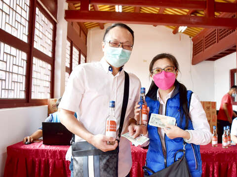 「2021金門369來金旅遊送振興券、抽金牌」活動，來自中壢的劉明鑫（左）、蔡瑞雯（右）夫婦於活動首日搶得頭香，成為第一組拿到金門振興券和酒精的旅客。（詹宗翰攝）