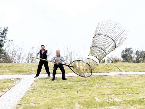 林務所邀請羅川敦、陳威伯兩位竹藝師傅與所內木工廠同仁合作，竹編3.5公尺高的竹製羽毛球及球拍，打造奧運羽球雙打金牌戰壓線IN的經典場景。（陳麗妤攝）